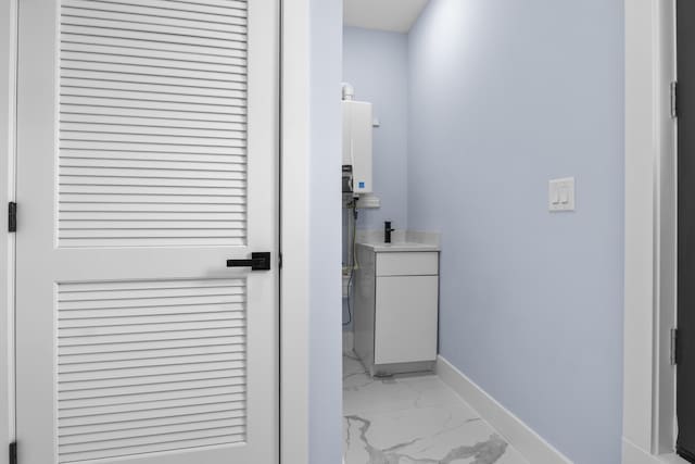 bathroom with baseboards, marble finish floor, water heater, and vanity
