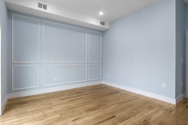 unfurnished room with visible vents, baseboards, and wood finished floors