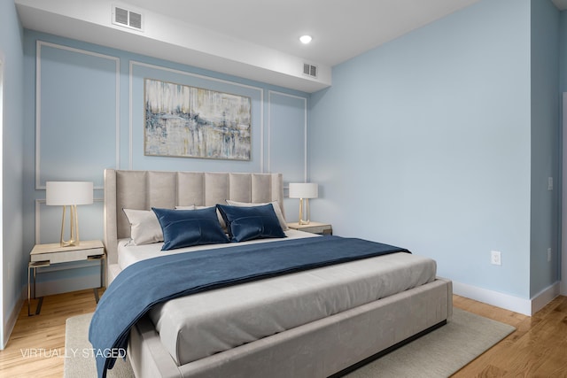 bedroom with visible vents, baseboards, and wood finished floors