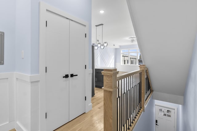 hallway with an upstairs landing and light wood-style flooring