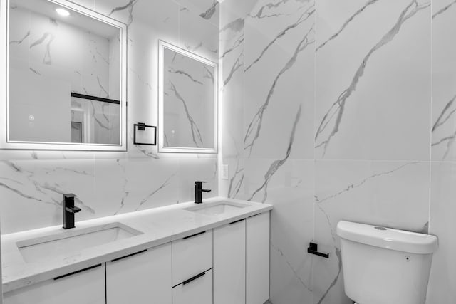 bathroom featuring a sink, tile walls, toilet, and double vanity