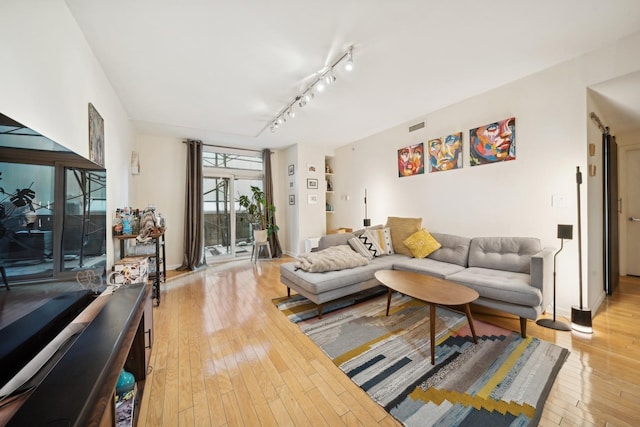 living room with track lighting and light hardwood / wood-style flooring