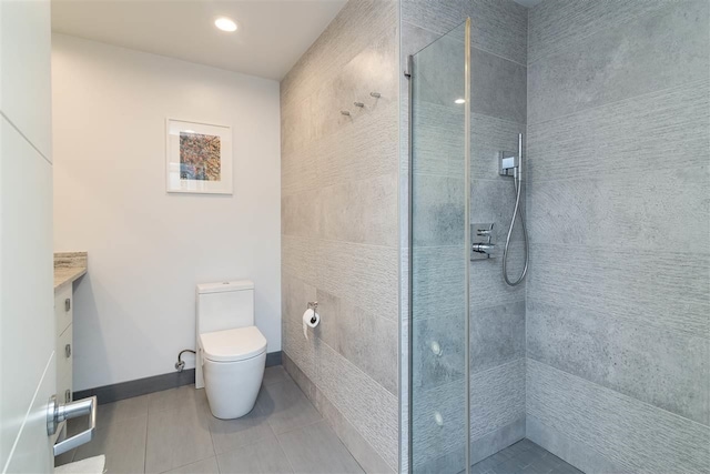 bathroom featuring toilet, vanity, a tile shower, and tile patterned flooring