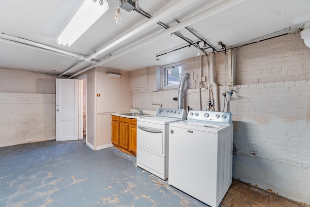 clothes washing area with washer and clothes dryer, cabinet space, and a sink