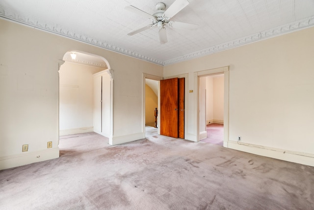 carpeted spare room with arched walkways and ceiling fan