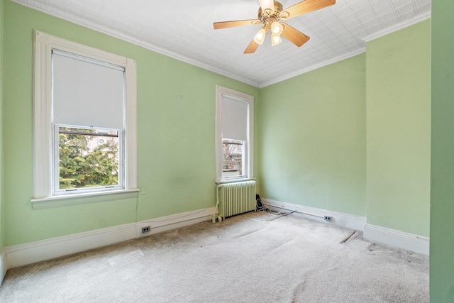 empty room featuring a wealth of natural light, radiator, crown molding, and carpet floors