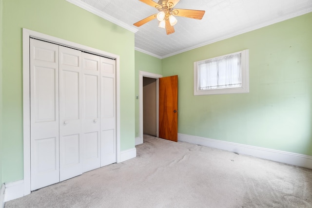 unfurnished bedroom with a ceiling fan, baseboards, carpet floors, ornamental molding, and a closet