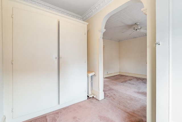 unfurnished room featuring crown molding, ceiling fan, decorative columns, light carpet, and arched walkways