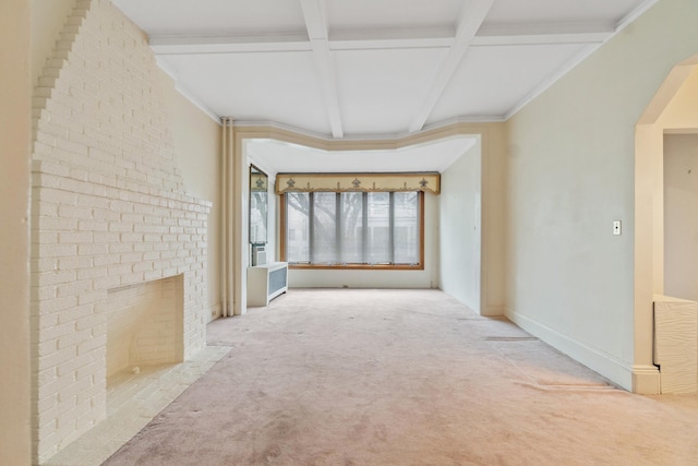 carpeted spare room with baseboards, beam ceiling, a fireplace, arched walkways, and coffered ceiling