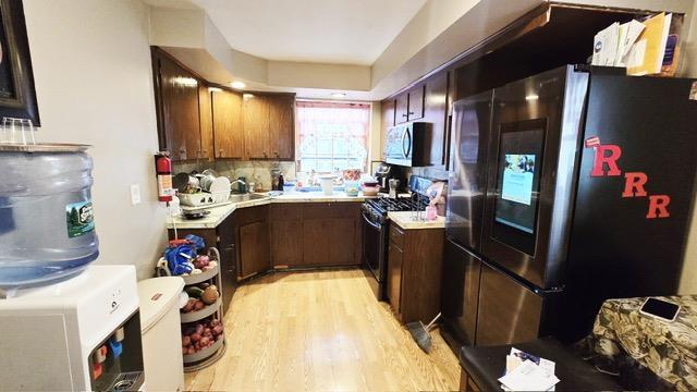 372 9th St, Fairview, NJ 07022 - kitchen featuring stainless steel appliances, light countertops, light wood finished floors, and backsplash