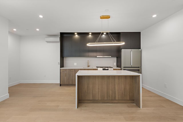 kitchen featuring a kitchen island, light countertops, a wall unit AC, light wood-type flooring, and freestanding refrigerator