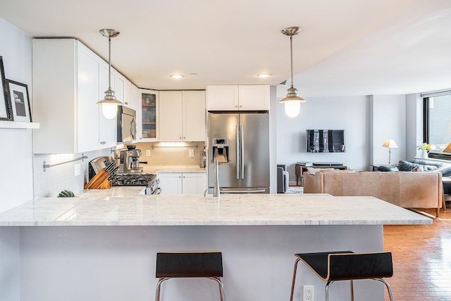 700 Grove St Unit 11P, Jersey City, NJ 07310 - kitchen featuring stainless steel appliances, a peninsula, glass insert cabinets, light wood-style flooring, and backsplash