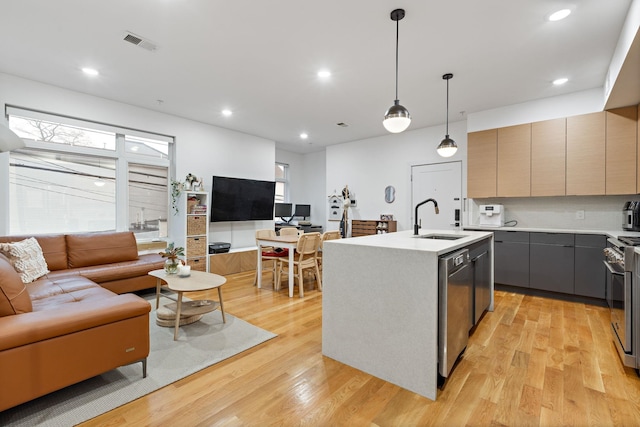 kitchen featuring sink, gray cabinets, hanging light fixtures, stainless steel appliances, and an island with sink