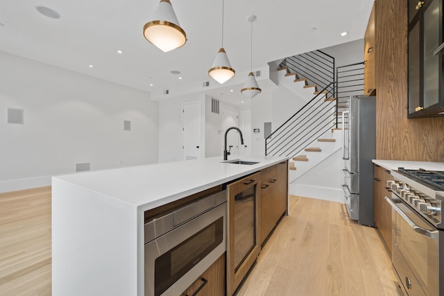 kitchen featuring wine cooler, stainless steel appliances, a sink, light wood finished floors, and modern cabinets