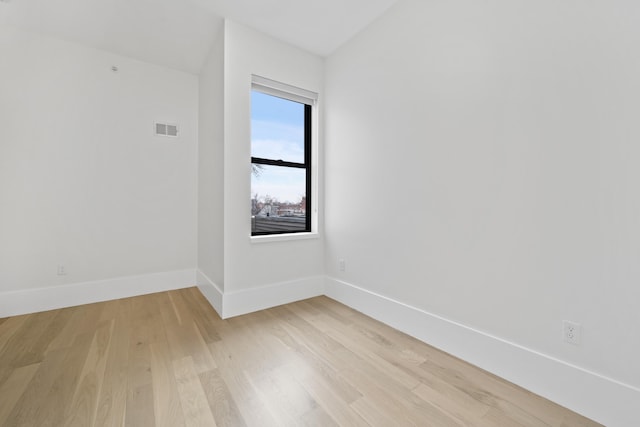 empty room with light wood-type flooring, visible vents, and baseboards