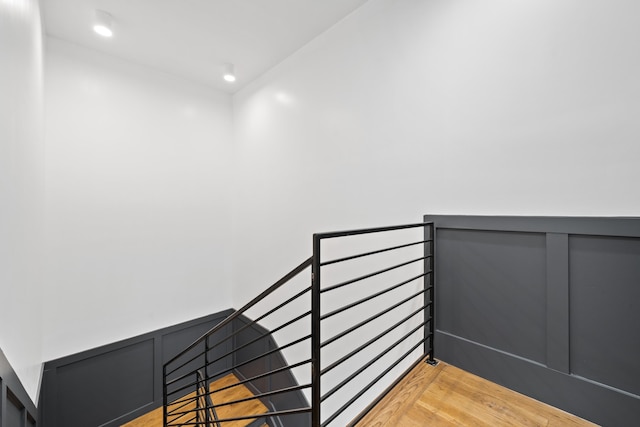 stairs with a wainscoted wall, a decorative wall, wood finished floors, and recessed lighting