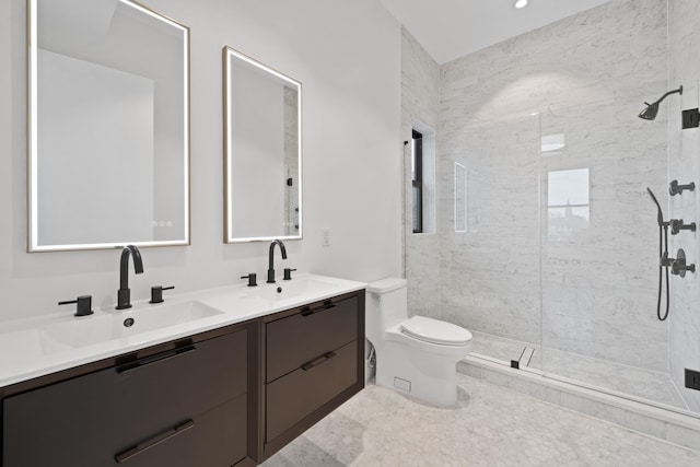 full bathroom featuring double vanity, tiled shower, a sink, and toilet