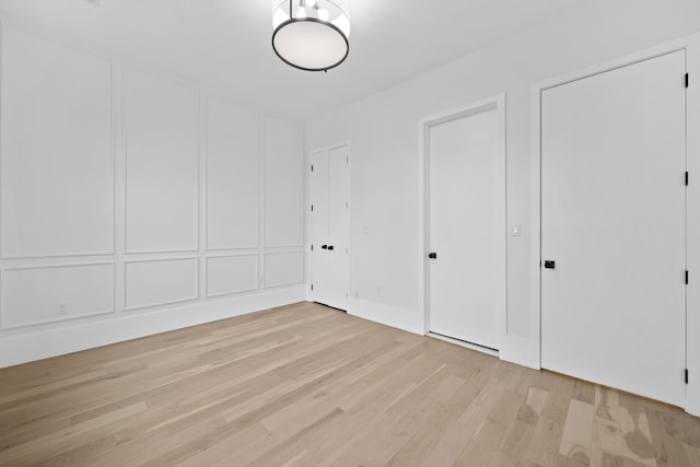 unfurnished bedroom with light wood-type flooring and a decorative wall