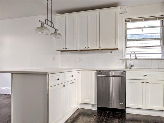 kitchen with hanging light fixtures, sink, stainless steel dishwasher, and white cabinets