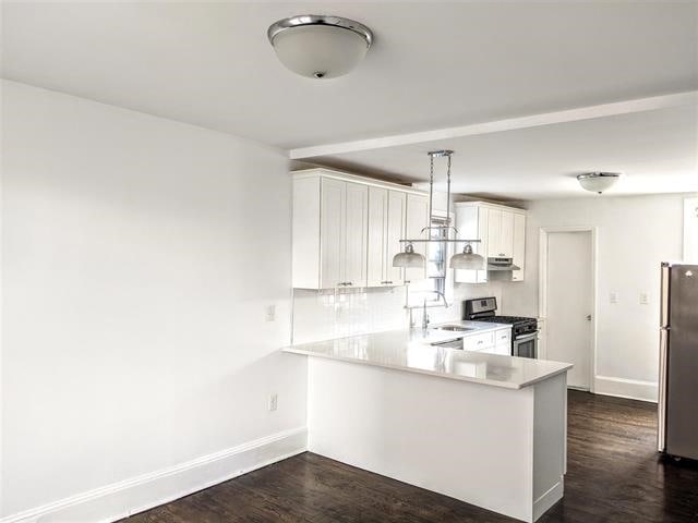 kitchen with appliances with stainless steel finishes, pendant lighting, white cabinetry, sink, and kitchen peninsula