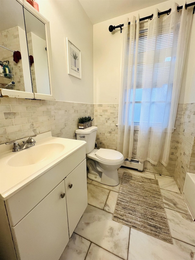 bathroom with vanity, tile walls, a baseboard radiator, and toilet