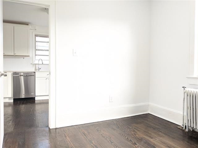 spare room featuring radiator, dark wood-type flooring, and sink