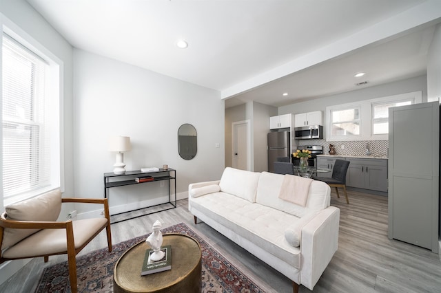 living room featuring a wealth of natural light, light wood-type flooring, baseboards, and visible vents