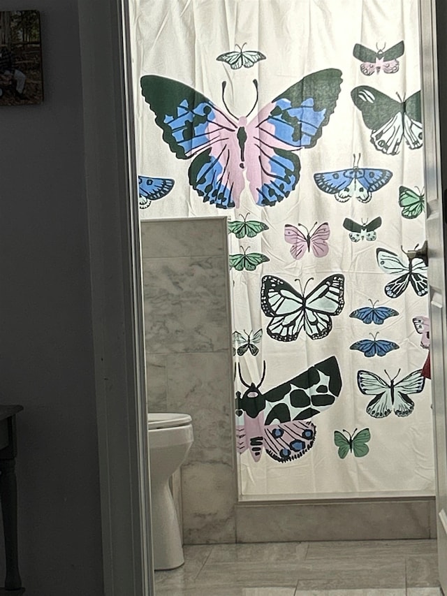 bathroom with a shower with curtain and toilet