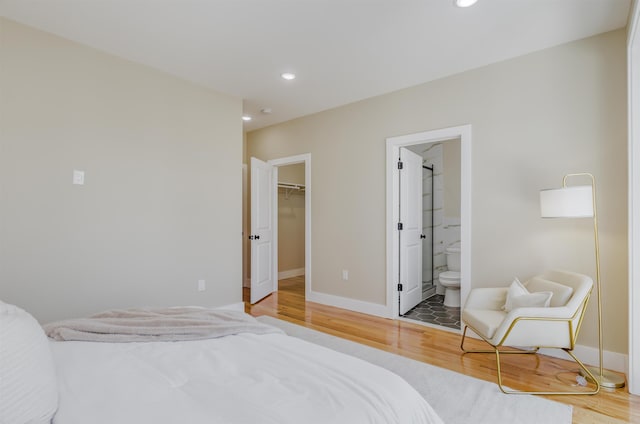 bedroom with recessed lighting, baseboards, a walk in closet, light wood finished floors, and ensuite bath