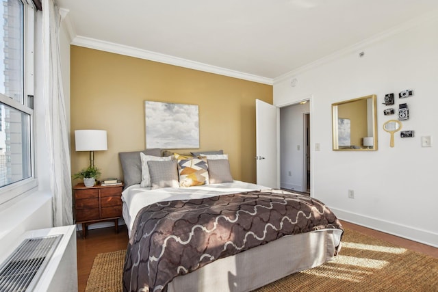 bedroom with ornamental molding, baseboards, and wood finished floors