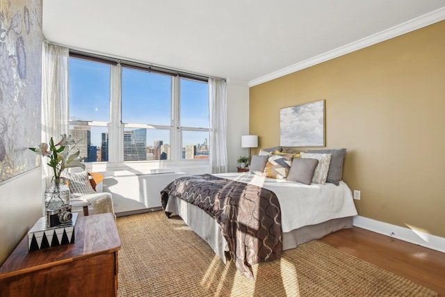 bedroom with light wood-type flooring, a city view, crown molding, and multiple windows