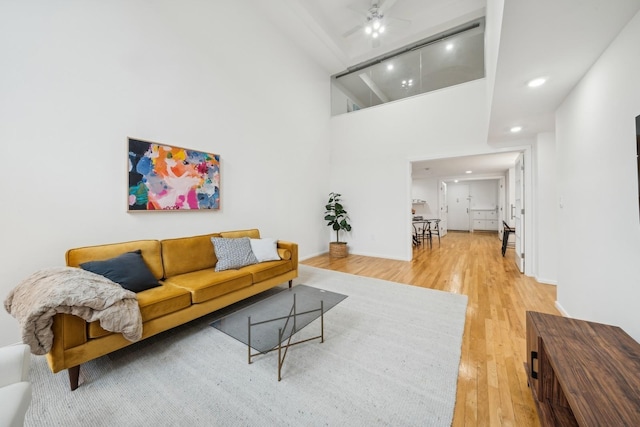 living room featuring a high ceiling, hardwood / wood-style flooring, and ceiling fan