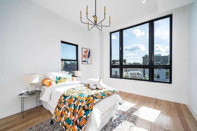 bedroom with wood finished floors, baseboards, and a chandelier