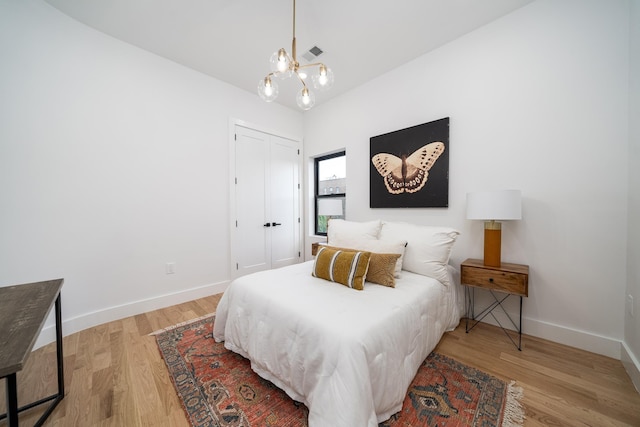 bedroom with visible vents, baseboards, wood finished floors, and a chandelier