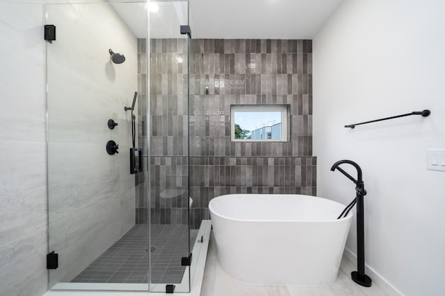 bathroom with a shower stall and a freestanding bath