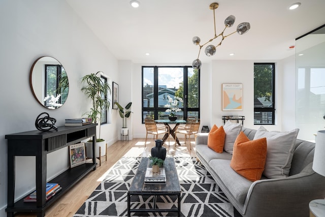 living area with recessed lighting, baseboards, a wall of windows, and light wood-style floors