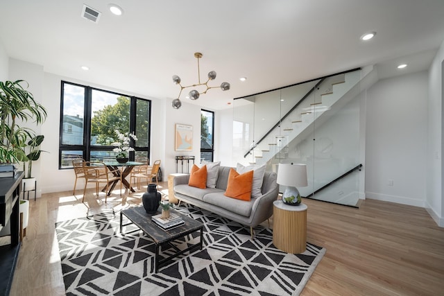 living room featuring stairway, visible vents, baseboards, light wood-style flooring, and recessed lighting