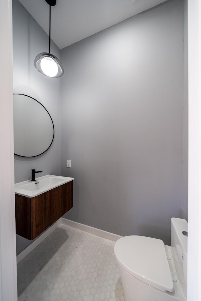 half bath featuring toilet, vanity, and baseboards