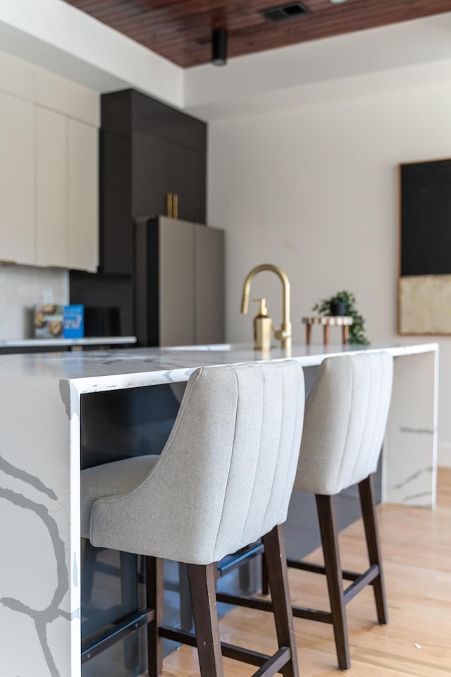 kitchen with visible vents, light wood-type flooring, modern cabinets, freestanding refrigerator, and white cabinets