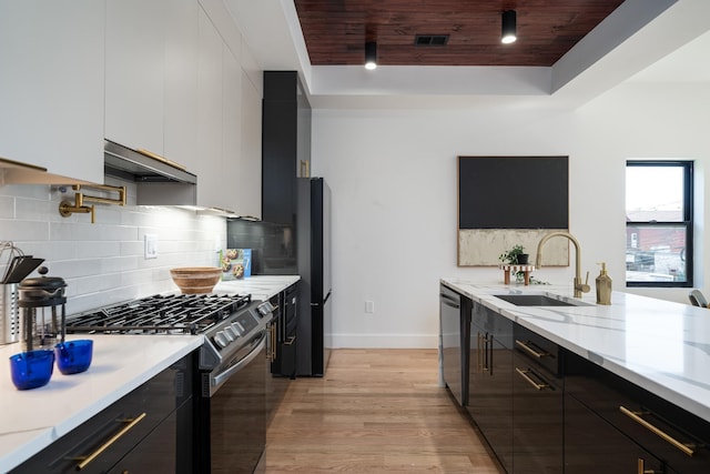 kitchen featuring a sink, under cabinet range hood, gas stove, modern cabinets, and stainless steel dishwasher