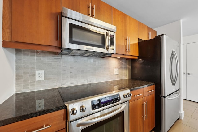 kitchen with stainless steel appliances, dark stone counters, light tile patterned floors, and tasteful backsplash