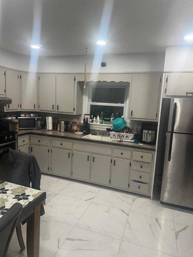 kitchen featuring stainless steel appliances, gray cabinetry, backsplash, and exhaust hood