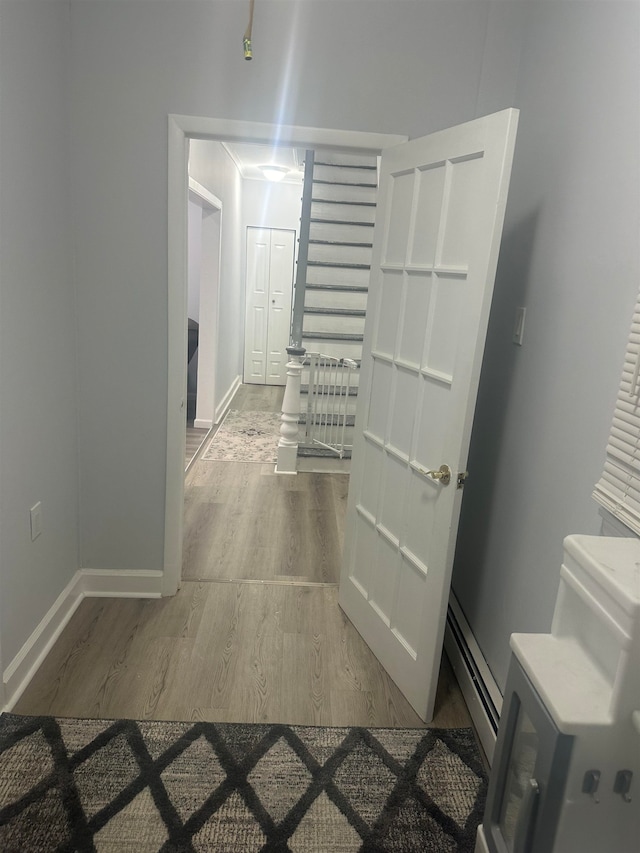 corridor with baseboard heating and wood-type flooring