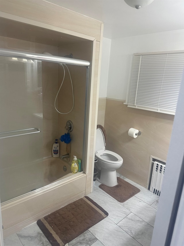 bathroom featuring toilet, radiator, bath / shower combo with glass door, and tile patterned floors