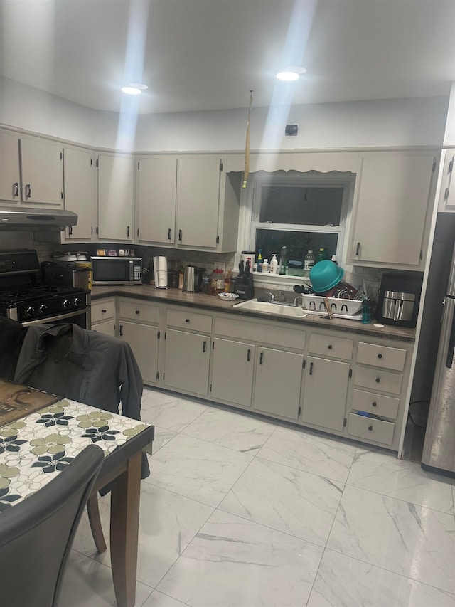 kitchen featuring stainless steel appliances, gray cabinetry, sink, and backsplash