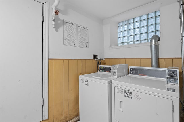 clothes washing area with wooden walls and independent washer and dryer