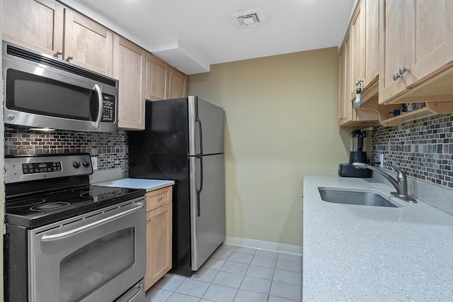 kitchen with sink, light tile patterned floors, appliances with stainless steel finishes, backsplash, and light brown cabinetry