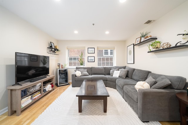 living room featuring beverage cooler, light wood-type flooring, and recessed lighting