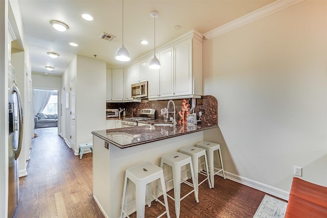 kitchen with pendant lighting, white cabinets, sink, kitchen peninsula, and stainless steel appliances