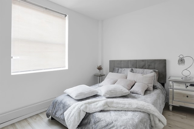 bedroom with a baseboard radiator and light hardwood / wood-style floors